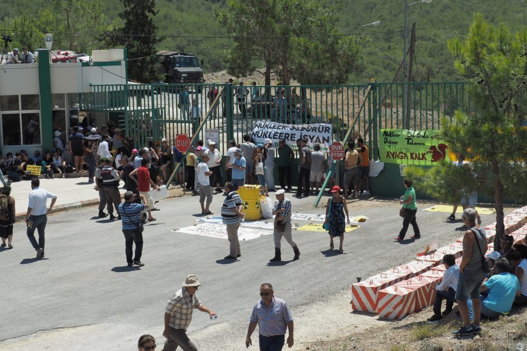 専門家の現地調査が行なわれる間、原発敷地前のゲートで抗議活動を行なう人々（7月11日、アックユ） 